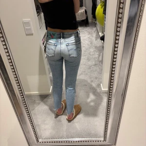 Blå jeans från Replay - Snygga blå jeans från Replay med broderad blomdetalj på baksidan. De har en ganska tight passform och är varken hög-eller lågmidjade.