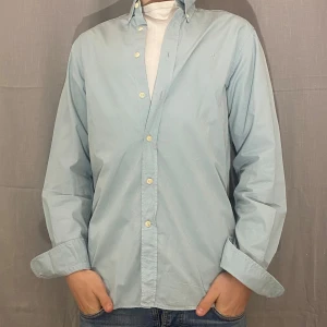 Ljusblå skjorta från Morris - Snygg ljusblå skjorta från Morris med klassisk krage och knappar framtill. Skjortan har en diskret broderad logga på bröstet och är tillverkad i ett bekvämt material. Perfekt för sommaren och våren. Storlek S men passar även M eftersom den är stor i storleken. Hör av er vid minsta fundering priset är även inte fast i sten ‼️‼️