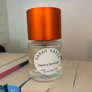 Sarah Baker Peach's Revenge parfym - Unik parfym från Sarah Baker, Peach's Revenge, skapad av Chris Maurice. Flaskan är cylindrisk i klart glas med en stor, metallic-orange kork som verkligen sticker ut. Doften är fruktig och modern, perfekt för dig som vill ha något annorlunda. Kanten på locket är något kantstött. Endast testad