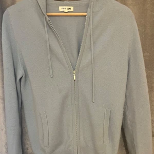 Ljusblå hoodie i kashmir från Soft Goat - Supermjuk ljusblå hoodie från Soft Goat i lyxig kashmir. Tröjan har dragkedja framtill, snörning i huvan och två fickor. Perfekt för dig som gillar en clean och chill stil med premiumkänsla.