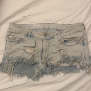 Ljusblå slitna jeansshorts med fransar - Säljer ett par ljusblå jeansshorts med låg midja och slitna detaljer. Fråga gärna om ni undrar nått💕