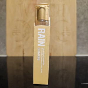 Shimang Scented Rain parfym - Parfymen Scented Rain från Shimang kommer i en smal glasflaska med guldfärgat lock och stilren gul förpackning. Doften har inslag av söt osmanthus och ger en fräsch, regnig känsla. Perfekt för dig som gillar unika och fräscha dofter.