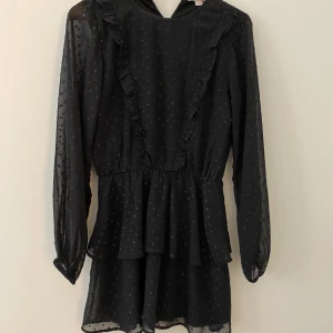 Svart prickig volangklänning från Gina Tricot - Supersöt klänning från Gina Tricot med små glitter prickar. Klänningen är använd och tvättad ett fåtal gånger🩷vid lappen finns en knapp som ska sättas ihop när du använder den🫶🏼