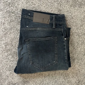 Tiger of Sweden svarta jeans - Snygga svarta jeans från Tiger of Sweden med diskret slitning framtill och klassisk femficksdesign. Jeansen har en mörk tvätt och raka ben, perfekt för en clean och stilren look. Materialet är mjukt och följsamt jeans.