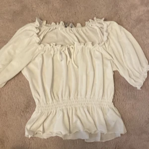 Vit blus med volang från Gina Tricot - Jätte fin blus från gina tricot, aldrig använd I och med att den är för stor för mig. Går att stretcha ut vid halsen och går även att knyta. Priser kan diskuteras💞Orginal pris runt 199kr
