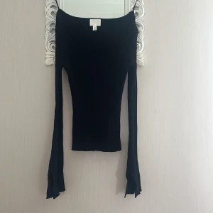Svart ribbad långärmad topp S - Svart ribbad långärmad topp från H&M med utsvängda ärmslut och rundad halsringning. Toppens material är stretchigt och sitter tight mot kroppen, perfekt för en stilren och trendig look.