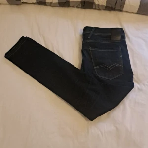 Replay anbass jeans i mörkblå denim - Snygga Replay jeans i mörkblå tvätt med klassiska fem fickor och kontrastsömmar. Modellen har raka ben och normal passform, tillverkade i mjukt jeanstyg. Perfekta för dig som gillar stilrena och tidlösa jeans med diskreta detaljer. Köpt för 1200