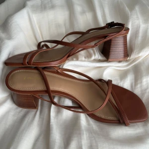 Bruna klackskor från & Other Stories - Snygga bruna sandaler från & Other Stories med smala remmar och fyrkantig tå. Skorna har en stabil, låg klack i trälook och är tillverkade i skinn. Använda 4-5 ggr 