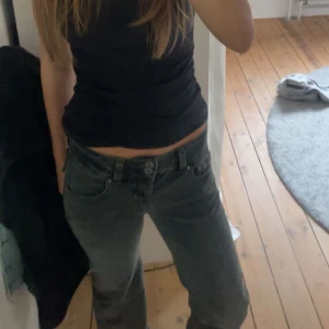 Svarta bootcut jeans med fickdetaljer - Snygga svarta jeans med bootcut passform och coola fickor med knappar och är tillverkade i ett mjukt denimtyg. Perfekta för dig som gillar en lite vidare siluett nertill och vill ha en trendig look.