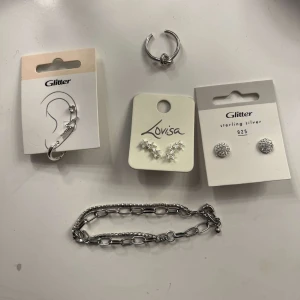 Smyckeskit silver  - Säljer ett kit med silversmycken: två par örhängen från Glitter (ett par studs med stenar, ett par med hängande design), ett par stjärnformade örhängen från Lovisa, en chunky silverring och ett coolt armband med kedjelänkar. Perfekt för att mixa och matcha till din stil! Skriv privat om ni vill köpa en specifik accessoar