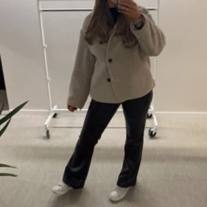 Beige teddyjacka  - Säljer min beige teddyjacka med oversized passform och svarta knappar framtill. Jackan har bred krage och långa ärmar, perfekt för dig som vill ha en mysig och trendig look. 
