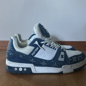 Louis Vuitton blåvita sneakers - Snygga Louis Vuitton sneakers i blått och vitt med klassiskt monogrammönster. Skorna har rund tå, snörning och coola detaljer på sulan. Tillverkade i en mix av skinn och textil för en lyxig känsla. Perfekta för dig som vill sticka ut med exklusiva sneakers.