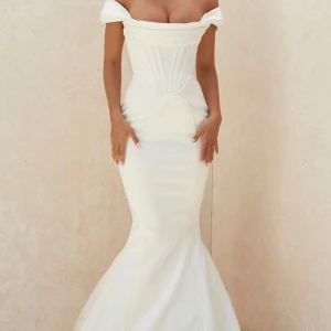 Vit långklänning med offshoulder - Superelegant vit långklänning med offshoulder och figurnära passform. Klänningen har en markerad midja, utsvängd nederdel och vacker v-ringning. Materialet är slätt och ger en lyxig känsla, perfekt för bal eller fest. Snygg och tidlös design som verkligen sticker ut. Använts en gång på en bröllopsmiddag, klänningen är lite smutsig på släpet men syns inte samt går att tvätta bort. Nypris är 10.000. Liten i storlek så en M passar en S. 