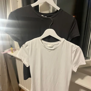 2-pack basic t-shirts mörkgrå & vit - Två klassiska t-shirts från H&M i mörkgrå och vitt. Båda har rund halsringning och korta ärmar. Perfekt för träning. 