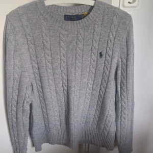 Kabelstickad Ralph lauren tröja - Grå kabelstickad tröja från Polo Ralph Lauren. Tröjan är i ny skick då den har används ett fåtal gånger. Säljs då den inte passar mig. Vid fler frågor, hör av er gärna 😊!