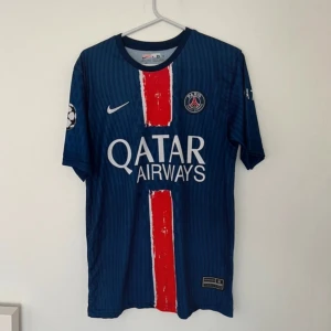 PSG 2024-25 hemmatröja - Hakimi  - PSG 2024/25 hemma tröja - Hakimi. Tröjan är helt oanvänd och nytt. Denna tröja är Champions League version vilket påminner när PSG vann UCL då hakimi gjorde ett fantastiskt mål. Tröjan finns i Vallentuna ifall ni befinner er i närheten men annans så är det frakt som gäller.