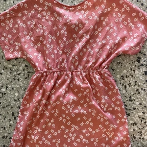 Rosa blommig kortklänning från MANGO - Supersöt rosa kortklänning från MANGO med vita småblommor över hela tyget. Klänningen har resår i midjan för en snygg passform och är tillverkad i ett mjukt, lätt material. Perfekt för varma dagar när du vill känna dig både bekväm och fin.