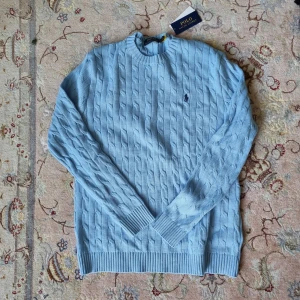 RALPH LAUREN KABELSTICKAD TRÖJA- ljusblå  - Säljer nu denna asfeta kabelstickade tröjan i ny skick från Ralph Lauren I storlek L. Kontakta gärna vid intresse. 