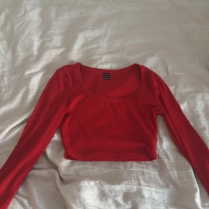 Röd croppad långärmad topp Shein - Snygg röd croppad topp från Shein med lång ärm och ribbad struktur. Toppen har en bred, rundad urringning och sitter tight. Perfekt för dig som gillar en enkel men trendig look.