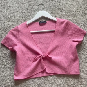 Rosa ribbad omlottopp från Bershka - Superfin rosa ribbad omlottopp från Bershka med knyt framtill.  Perfekt för dig som gillar färg och vill sticka ut lite extra.