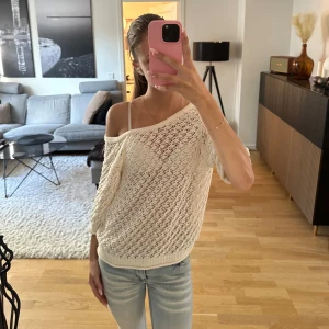 Vit stickad kofta med knytband - Superfin vit stickad kofta med genombrutet mönster och knytband framtill. Koftan har en loose passform, trekvartsärmar och kan bäras offshoulder för en chill vibe. Går att använda både som en t-shirt med knyt i ryggen eller som en kofta med knyt framtill 