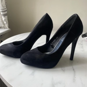 Svarta pumps från NLY Shoes, strl 39 - Klassiska svarta pumps från NLY Shoes i storlek 39. Skorna har rund tå, hög klack och är klädda i mjuk mockaimitation. Perfekta för dig som vill ha en stilren och tidlös look med lite extra höjd.