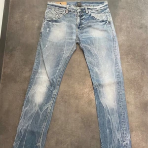 Dondup George - Säljer ett par ljusblå Dondup George jeans med snyggt slitna detaljer och slimmade ben. Tillverkade i bomull med en skön passform som funkar till allt. Made in Italy.