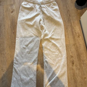Grå mjukisbyxor från Gina Tricot - Snygga ljusgrå mjukisbyxor från Gina Tricot med resår i midjan och snörning. Byxorna har en relaxed passform och är perfekta för chill dagar. Tillverkade i mjukt material som känns skönt mot huden.