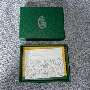 Vit designer plånbok med mönster - Säljer en stilren vit plånbok med det ikoniska mönstret och diskret logga framtill. Plånboken har flera kortfack och är tillverkad i exklusivt skinn. Perfekt för dig som vill ha något lyxigt och unikt i fickan. Boxen medföljer ej!