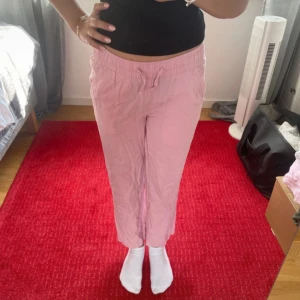 Ljusrosa linnebyxor med snörning - Säljer ett par ljusrosa linnebyxor med avslappnad passform och snörning i midjan. Byxorna är raka i modellen och perfekta för en chill och bekväm stil. Superlätta och luftiga, passar perfekt till sommaren.