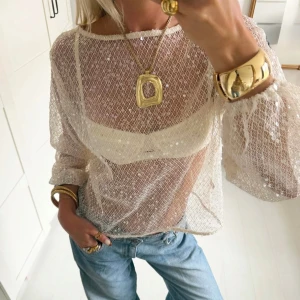 Vit transparent blus med paljetter (Viral Zara top) - Superfin transparent vit blus med nätstruktur och små paljetter som ger ett glittrigt intryck. Långärmad modell med lös passform och rund halsringning. Perfekt att styla med jeans eller kjol för en trendig look.