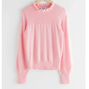 Ljusrosa Other stories stickad tröja - Supersöt ljusrosa stickad tröja från & Other Stories med volangkant vid halsen och diskret strukturmönster upptill. 