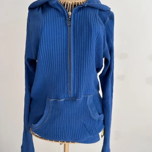 Blå ribbad hoodie från Bik Bok - Blå ribbstickad hoodie från Bik Bok med dragkedja framtill och stor huva. Tröjan har känguruficka och en patch nertill. Perfekt för dig som gillar en avslappnad och sportig stil. Materialet känns mjukt och bekvämt. Stl L men tycker den är mer som M.