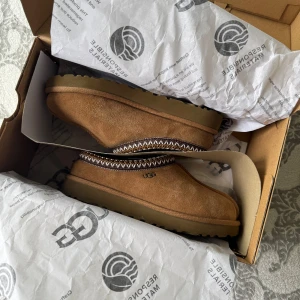 UGG Tasman W - UGG Tasman W – Nästan nya & superfräscha! 🔥  Säljer ett par UGG Tasman tofflor (W) i mycket bra skick, knappt använda och endast inomhus. Perfekta för dig som vill ha det bekvämt men ändå stylish – passar lika bra till mysoutfiten som till en chill streetlook 🧸✨                                                💸Först till kvarn – passa på innan de försvinner!  📍Kan mötas upp eller skickas!