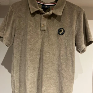 Beige frotté pikétröja WHO's A.C.E XS - Säljer en grön pikétröja i mjuk frotté från WHO's A.C.E. Tröjan har klassisk krage, korta ärmar och knäppning med två knappar. På bröstet finns en broderad logga i mörkblått och guld. Perfekt för en chill och stilren look. Är i storlek XS men sitter som S. Bra i skicket! Bara att höra av sig vid eventuella frågor!😉
