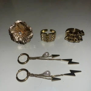 Guldiga ringar & örhängen från Edblad💗 - Säljer tre unika guldiga ringar: den med blomman är från Kappahl, mitten ringen från SHEIN och ringen till höger ör från Edblad i storlek 18:50. Guldörhängena är också från Edblad och ingår även.💗