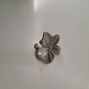 Blomma ring - Superfin ring med en blomma på! Den är väldigt sparsamt använd och har inga defekter, köpt på en marknad på Gotland så jag vet tyvärr inte vad det är för material. Silverfärgad, tveka inte att höra av dig vid frågor eller funderingar 💕 Ringen är sjusterbar I storleken 