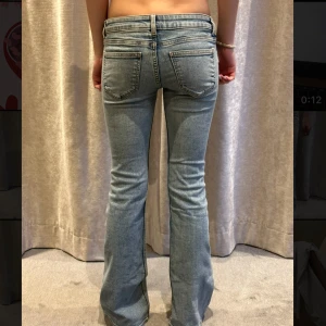 Bootcut ljusblå jeans med slitningar - Ljusblå jeans med bootcut passform och slitna detaljer på låren och knäna. Klassisk femficksmodell med låg midja och dragkedjegylf. Jeansen har en avslappnad vibe och är perfekta för dig som gillar en lite retro look.Midjemått: 35 cm tvärsöver, innerben: 81 cm