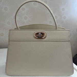 Beige handväska med guldigt spänne - Liten, elegant beige väska med gulddetalg💛