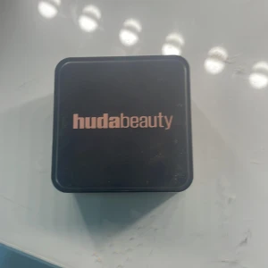 Huda Beauty löspuder BLONDIE - Löspuder från Huda Beauty. Pudret är ljust beige och ger en matt finish. Perfekt för att fixera sminket och ge en jämn hudton. Kommer i en praktisk förpackning med sil för enkel applicering. Säljer pågrund av att jag köpte fel färg . Har använt fåtal gånger 