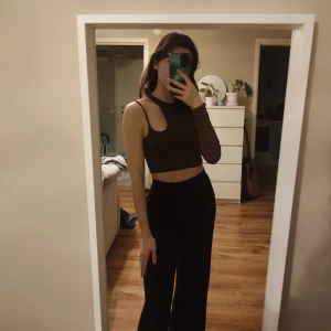 Brun asymmetrisk croppad topp från Pull&Bear - Säljer en brun croppad topp från Pull&Bear med asymmetrisk design i lätt ribbat tyg. Toppen har en lång ärm och en armlös sida. Väldigt fin och sensuell. Det står storlek M på tröjan men skulle säga att den är en S.