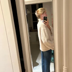 Vit/beige kashmir tröja - Säljer en beige stickad polotröja med oversized passform. Tröjan har långa ärmar och hög polokrage, perfekt för kyligare dagar. Enkel och stilren design som passar till det mesta.