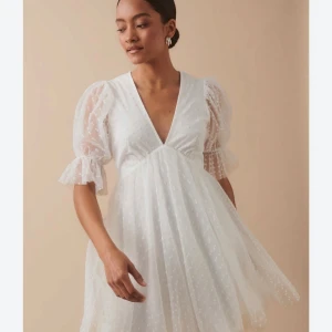 Vit kortklänning med puffärm från Gina Tricot - Superfin oanvänd vit kortklänning från Gina Tricot med v-ringning och puffärmar. Klänningen har transparenta ärmar med prickigt mönster och volangdetalj vid ärmslut. Perfekt för studenten och sommarens alla tillfällen!