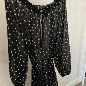 Svart prickig långklänning från Lindex - Svart långklänning från Lindex, oanvänd! Passar bra som strandklänning eller något under då den är transparent :)