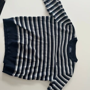 Marinblå och vit randig tröja från Sebago - Säljer en klassisk marinblå och vit randig tröja från Sebago i storlek medium. Tröjan har långa ärmar, ribbade muddar och är tillverkad i ett mjukt, stickat material. Perfekt för en stilren och avslappnad look.