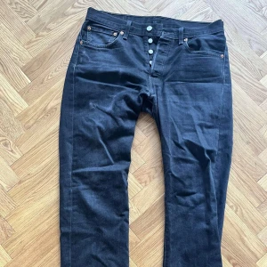 Svarta jeansbyxor, Levis, 501 - Svarta jeans från Levis, modell 501. Strl 32/32. Är ett litet märke på ena fickan från mobilen, annars mkt bra skick.