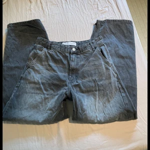 Grå jeansbyxor från Bershka - Säljer ett par grå jeansbyxor från Bershka skater jeans modellen. Byxorna har normal passform och stängs med knapp och dragkedja. Perfekta för en avslappnad och stilren look.