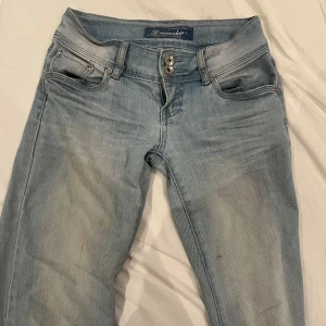 Ljusblå lågmidjade jeans från Zaramodav - Säljer ett par ljusblå jeans från Zaramodav med låg midja och klassisk femficksdesign. Jeansen har raka ben och stängs med dubbla knappar och dragkedja. Perfekta för en avslappnad stil.