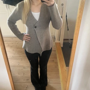 Beige omlott kavaj i ull - Säljer en beige omlott kavaj med en knapp framtill. Koftan har 89% ull som gör den varm och skön. 