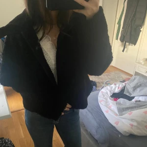 Svart teddyjacka - Mysig svart teddyjacka med dragkedja. Perfekt för kyligare dagar och ger en trendig look. Jackan har långa ärmar och en bekväm passform.